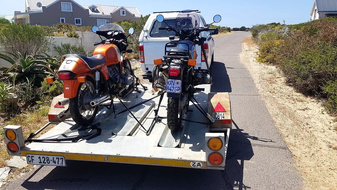Two classic motorcycles secured on a trailer with South African plates